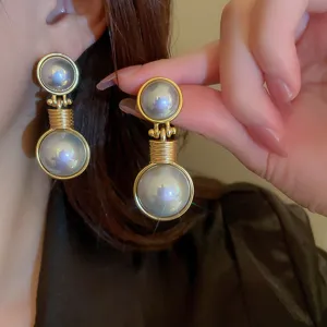 Close-up detail of vintage style pearl drop earrings with elegant gold finish and lustrous shine.