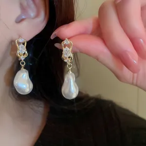 Close-up detail of vintage baroque pearl earrings with sparkling crystal studs and gold finish.