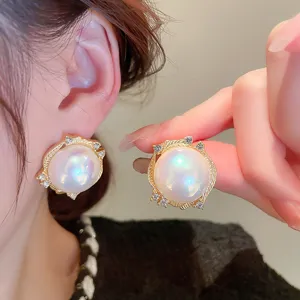 Vintage court style pearl stud earrings detail, elegant filigree metal with sparkling stones.