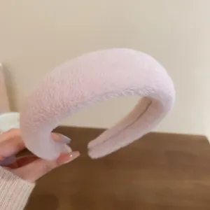 Nahaufnahme des weichen rosa Plüsch-Haarreifs, die flauschige Textur und das Design zeigt.