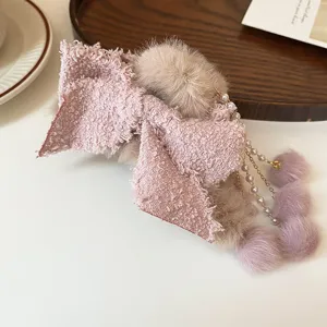 Flauschige pinke Schleifen-Haarspange mit Perlenquasten, Detailansicht plüschiges Winter-Accessoire.