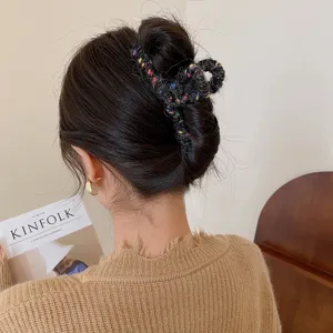 Detailaufnahme einer Tweed-Haarklammer am Hinterkopf, stilvolles strukturiertes Haaraccessoire.
