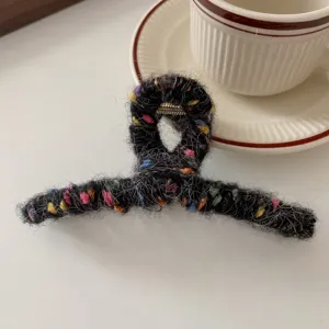 Nahaufnahme einer flauschigen schwarzen Haarklammer mit bunten Punkten für den Alltag.