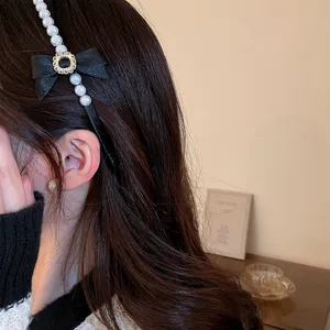 Gedetailleerd uitzicht op de zwarte fluwelen haarband met parels en strass-details.