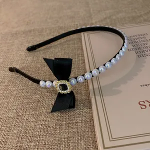 Franse vintage stijl parel haarband met zwarte strik, elegante haaraccessoire detailweergave.