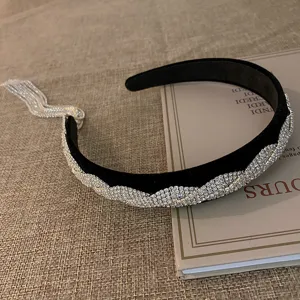 Exclusief detail van de zwarte fluwelen haarband met sprankelende strass-steentjes en kwastje.
