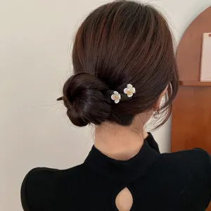 Close-up detailopname van een houten Chinese haarspeld met witte bloemen in een knot.