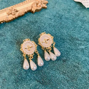 Close-up detail of vintage gold baroque bee pearl earrings with hanging teardrop pearls.