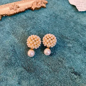 Detail shot of vintage pearl cluster earrings showcasing delicate gold metalwork and texture.
