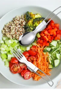 Set di cucchiaio e forchetta pieghevoli in acciaio inossidabile in una ciotola di insalata.