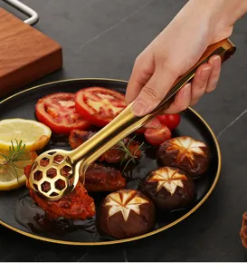 Dettaglio della pinza per alimenti in acciaio dorato con design a nido d'ape per grigliata.