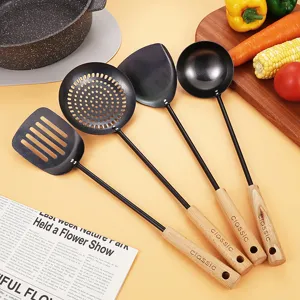 Black cast iron kitchen utensil set with beech wooden handles, spatula, slotted spoon and ladle.