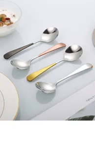 Close-up detail view of stainless steel round spoons with multi-color handles on a bright table.