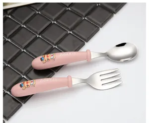 Detailaufnahme des Edelstahllöffel- und Gabelsets für Babys mit rosa Zeichentrickgriffen.