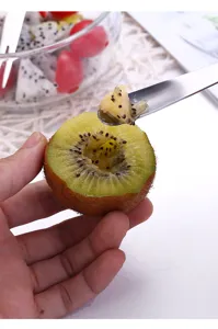 Detalle de la cuchara tenedor de acero inoxidable que muestra el uso práctico para frutas.