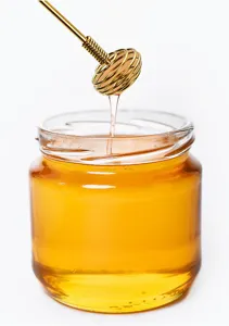 Gold stainless steel honey dipper detail shot, perfect for stirring tea, coffee and cocktails.