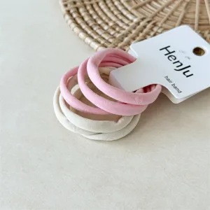Detailopname van minimalisten hoogelastische haarbanden set in roze en beige, zachte handdoekstof.