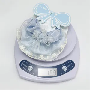 Blue plaid hair scrunchie with delicate white lace trim, shown on scale for detail.