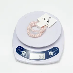 Close-up detail shot of pink clear telephone wire hair ties with tag on a digital scale.