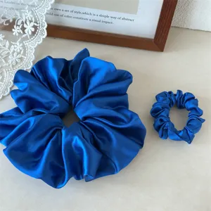 Detailed view of blue satin hair scrunchies, large and small sizes for everyday styling.