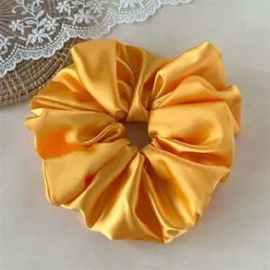Large yellow satin hair scrunchie for women, soft elastic hair tie and daily styling hair accessory.