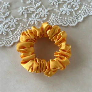 Yellow satin scrunchie for women, elegant hair tie with smooth fabric and high elasticity.