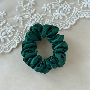 Dark green satin hair scrunchie detail shot, smooth glossy fabric and elastic band design.