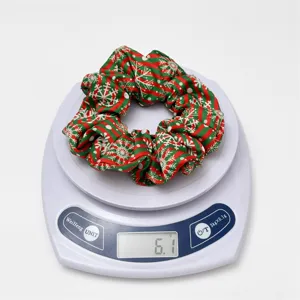 Detail view of Christmas holiday red and green snowflake print elastic hair scrunchie accessory.