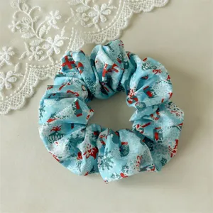 Blue satin Christmas scrunchie with holiday snowflake and gift prints for stylish hair styling.
