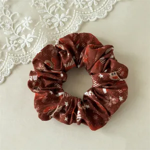 Detailed view of brown Christmas hair scrunchie with cute holiday snowflake and reindeer prints.