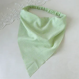 Pañuelo triangular verde a cuadros en detalle, diadema elástica para estilo diario de mujer.