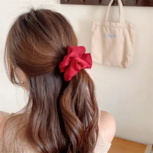 Detailansicht eines roten Satin Haargummis im braunen Haar, elegantes plissiertes Haarband