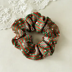 Close-up detail of the Christmas themed hair scrunchie with red green stripes and snowflakes.