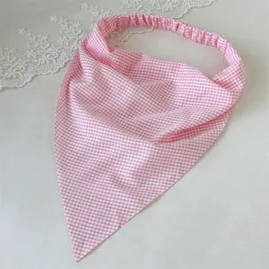 Vista detallada de la diadema triangular con patrón de cuadros rosa, accesorio elástico.