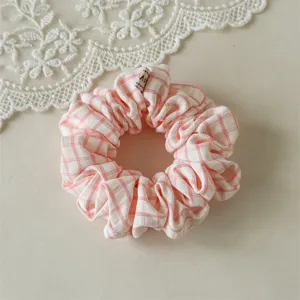 Gros plan du chouchou en tissu à carreaux roses et blancs, design doux et élastique.