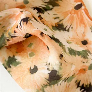 Close-up of soft floral chiffon fabric featuring a vibrant orange and green tie-dye print.