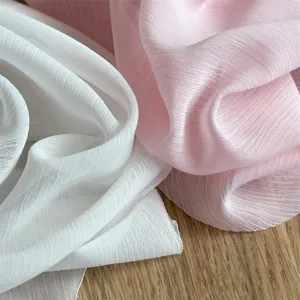 Dettaglio di tessuto in chiffon di alta qualita, morbida texture plissettata bianco rosa.
