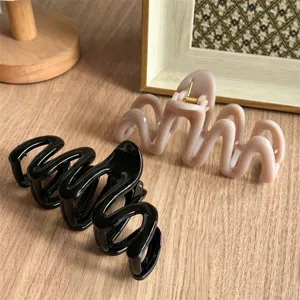 Detail view of wavy hair claw clips in black and grey, showing unique zig-zag design.