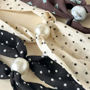 Detailed view of vintage polka dot and geometric thin silk scarf necklaces with large pearl buckles.