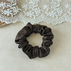 Close-up detail of dark brown satin hair scrunchie, smooth silk texture for daily styling.