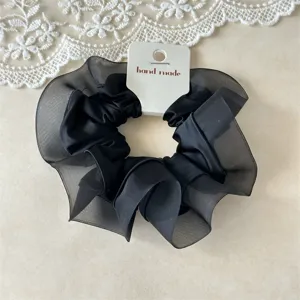 Detailaufnahme eines eleganten schwarzen Organza und Satin Haargummis für stilvolles Haar.