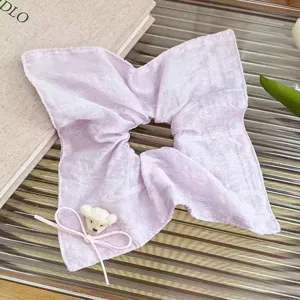 Close-up detail of the sweet pastel purple hair scrunchie with a cute plush bear and ribbon.
