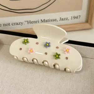 Detail van een beige acetaat haarlemmer met kleurrijke bloemen en sprankelende strass-steentjes.