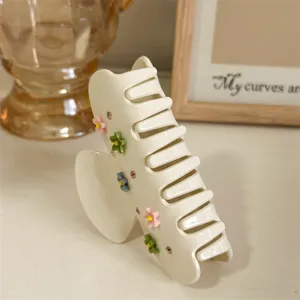 Gedetailleerd overzicht van stijlvolle acetaat haarclip met strass en kleine bloemen.
