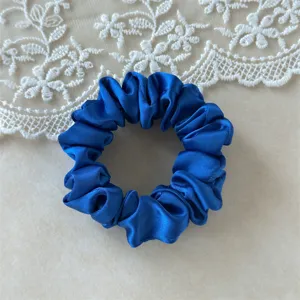 Close-up of a vibrant royal blue satin hair scrunchie featuring a glossy texture and soft surface.