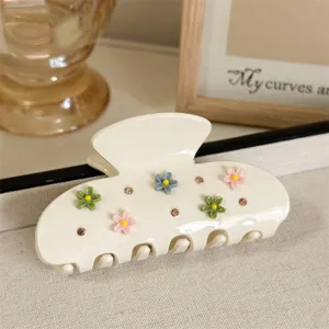 Detailopname van witte acetaat haarhaak versierd met kleurrijke harsbloemen en strass steentjes.