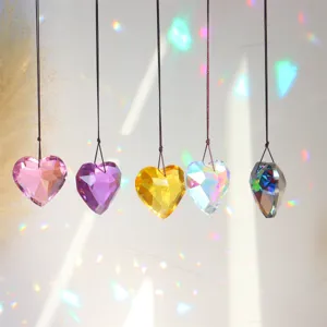 Close-up of colorful crystal heart suncatcher pendants hanging with rainbow light effects.