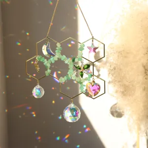 Crystal suncatcher detail hanging with honeycomb metal frame and natural green stone chips.