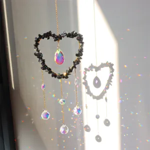 Crystal suncatcher detail shot showing rainbow prism reflections on wall with black stone heart.