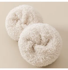 Gros plan de chaussettes de sommeil en polaire corail moelleuse, tissu chaud et doux duveteux beige.